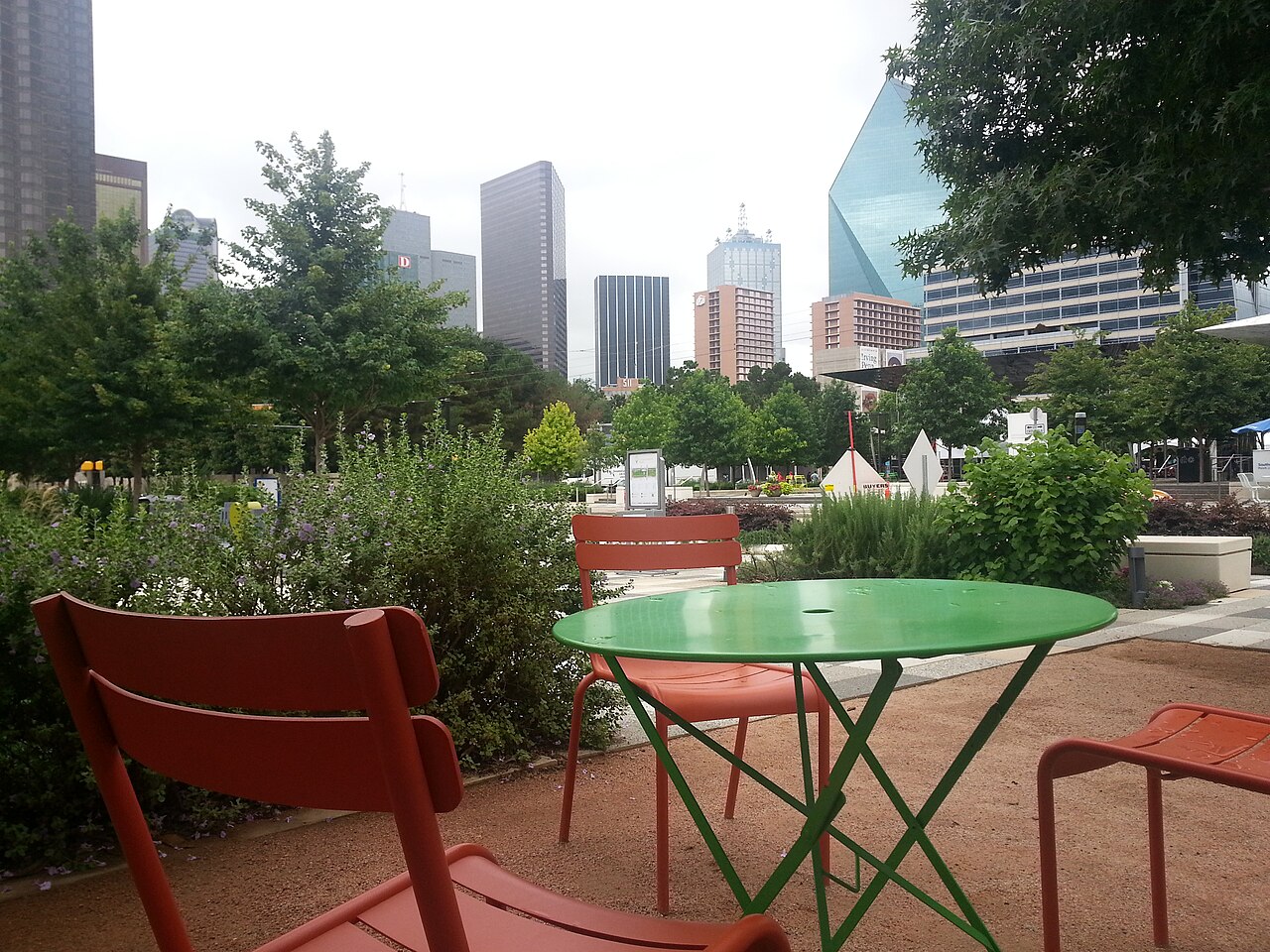Trees and paths in Klyde Warren Park beneath downtown Dallas towers